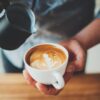 barista fazendo desenho em um café que está em uma xícara branca