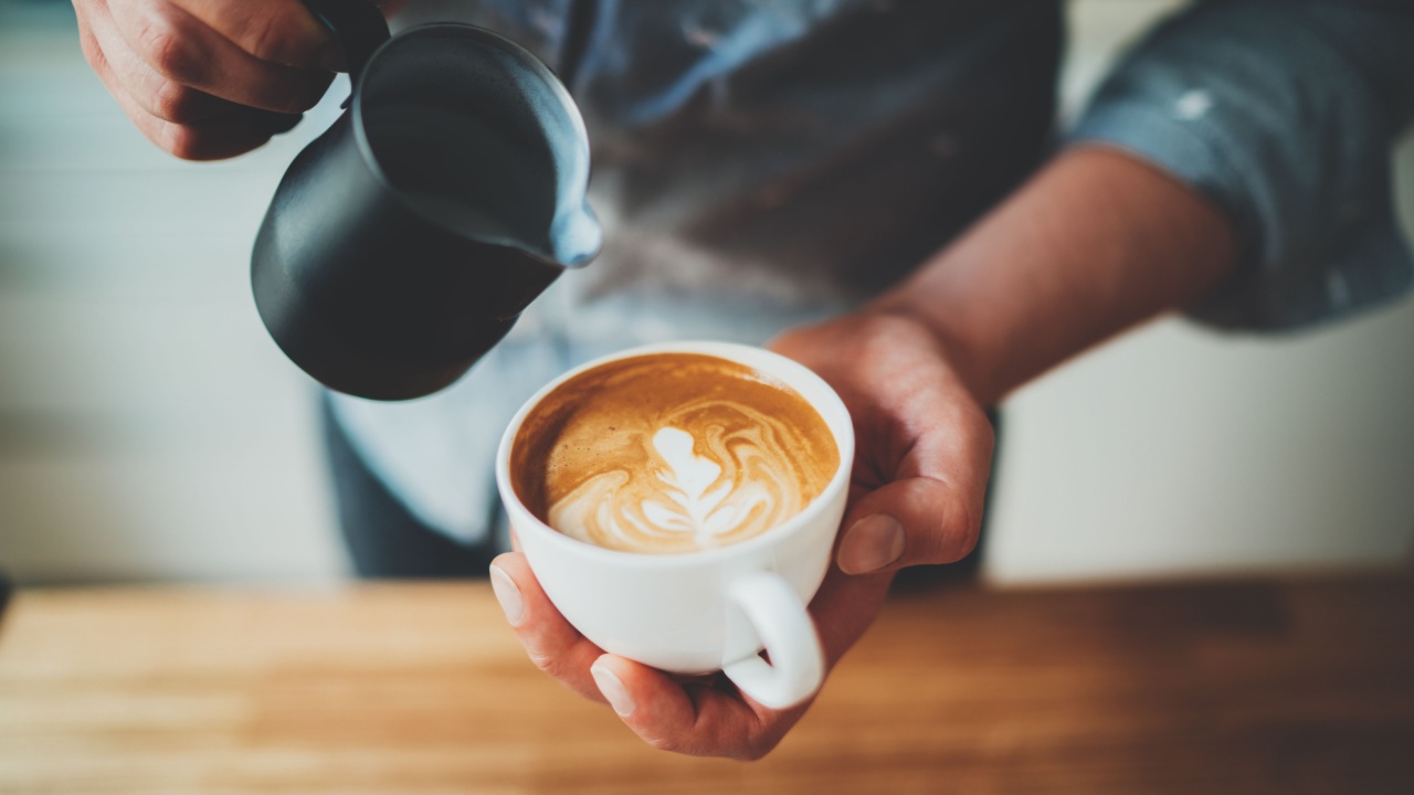 barista fazendo desenho em um café que está em uma xícara branca