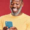 Estúdio, homem sorrindo para o celular. Pessoa feliz lendo site.