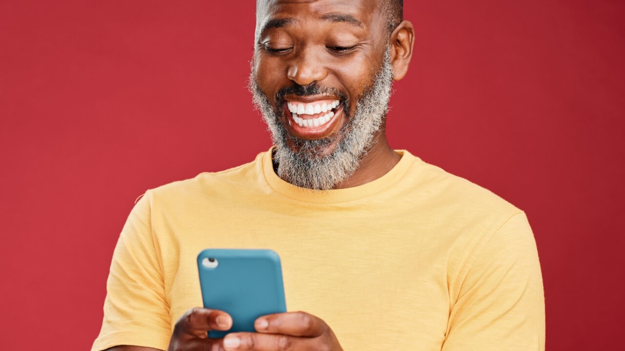 Estúdio, homem sorrindo para o celular. Pessoa feliz lendo site.