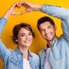 casal com as mãos se complementando e formando um coração em fundo amarelo