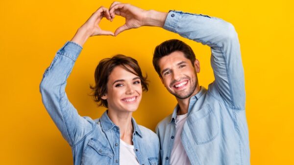 casal com as mãos se complementando e formando um coração em fundo amarelo