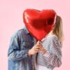 Casal se beijando atrás de balão em forma de coração