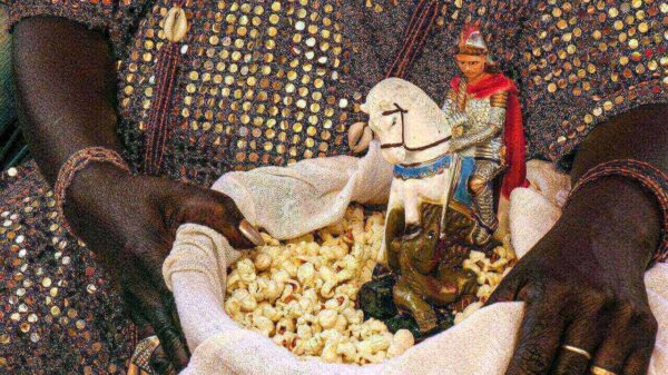 Santa Mãe do Candomblé segurando uma cesta com pipoca e uma imagem de São Jorge (Ogum).