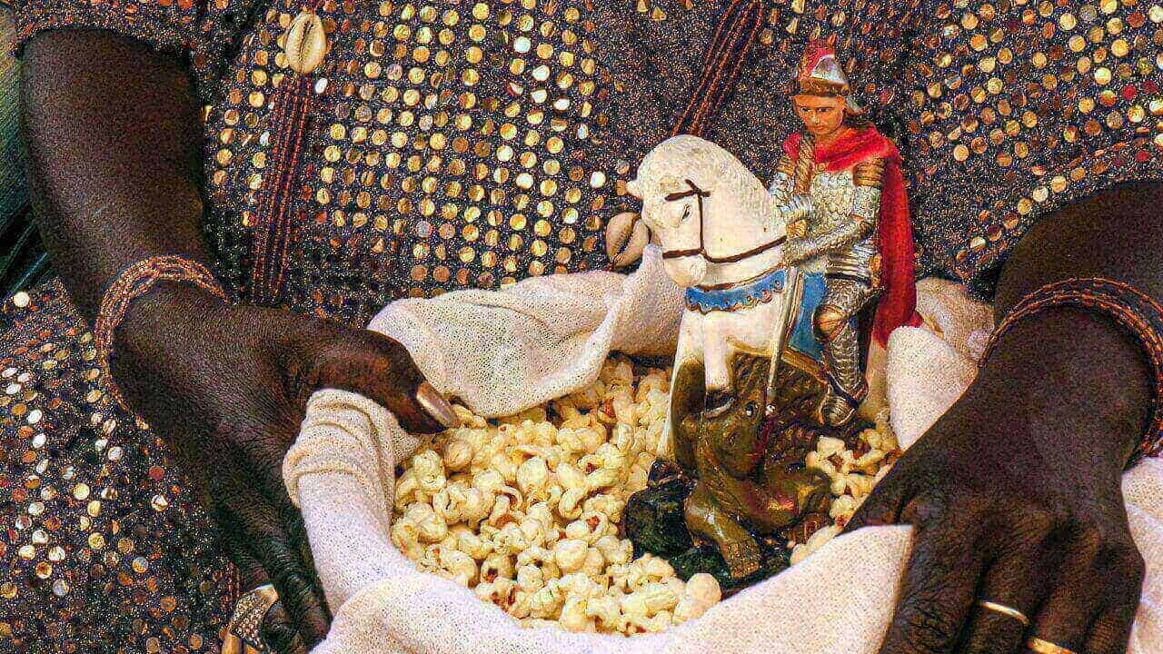 Santa Mãe do Candomblé segurando uma cesta com pipoca e uma imagem de São Jorge (Ogum).