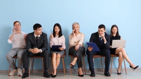 Candidatos esperando para fazer uma entrevista de emprego na frente de uma parede azul.