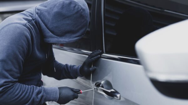 homem tentando abrir a porta de um carro assalto