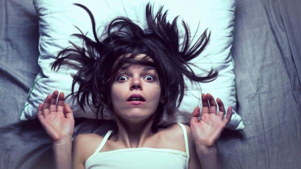 Mulher na cama assustada com terror noturno