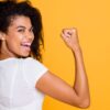 mulher de perfil mostrando o braço semelhante a famosa imagem feminista em fundo amarelo