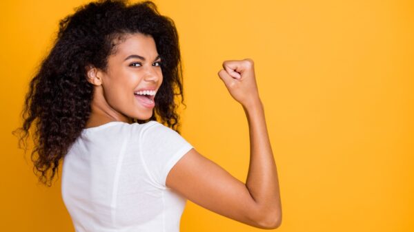 mulher de perfil mostrando o braço semelhante a famosa imagem feminista em fundo amarelo