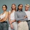 Grupo de mulheres juntas em um estúdio. Quatro mulheres olhando para a câmera em pé contra um fundo de estúdio.