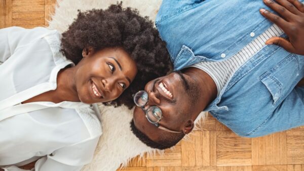 casal deitados no chão, encima de um tapete. se olhando e sorrindo