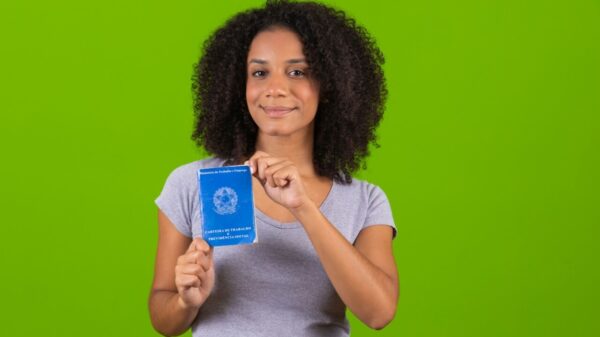 Mulher segurando uma Carteira de Trabalho e Previdência Social.