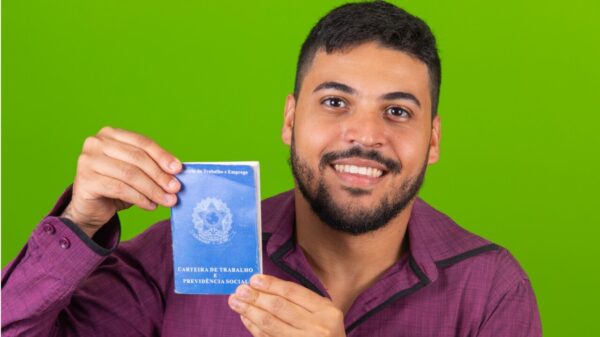 Homem segurando uma Carteira de Trabalho e Previdência Social.