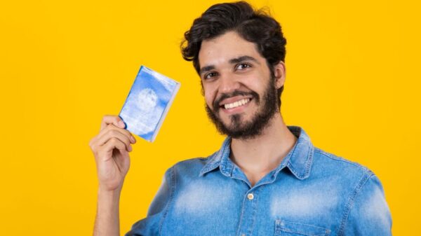 Homem segurando uma carteira de trabalho e previdência social.
