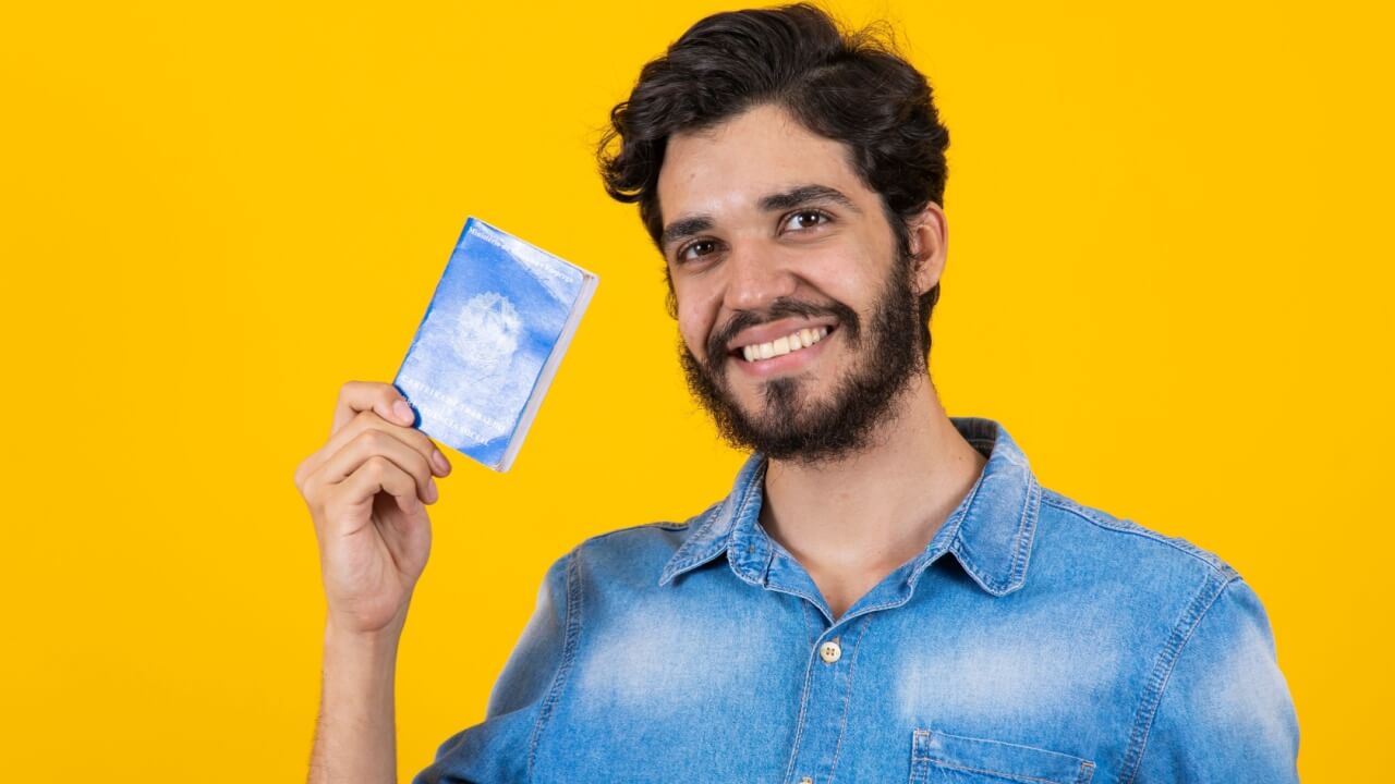 Homem segurando uma carteira de trabalho e previdência social.
