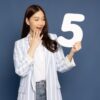 mulher de traços asiáticos segundo o numero cinco branco e grande em fundo azul escuro