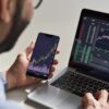 fotografia de um homem vendo finanças no notebook e no celular