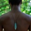 foto de um homem negro de costas em uma mata com objetos da religião africana