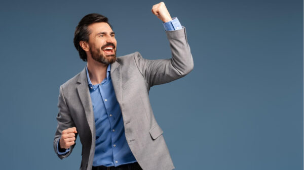 Empresário demonstrando estar feliz e bem-sucedido, isolado em um fundo azul, comemorando. Conceito de sucesso, carreira e negócio.