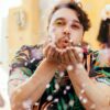 homem assoprando confete em uma festa de carnaval