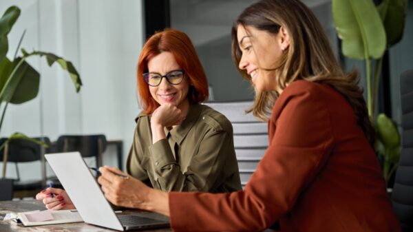 duas mulheres com roupas sociais trabalhando com o notebook em um escritório