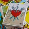 carta do tarot com um coração com espada e ao fundo outras cartas de tarot espalhadas