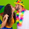 casal de foliões com suas fantasias de carnaval se beijando em um fundo verde