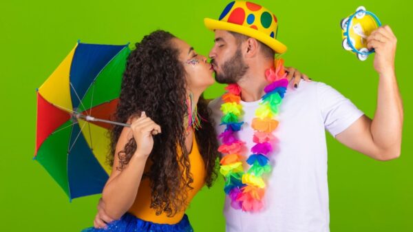 casal de foliões com suas fantasias de carnaval se beijando em um fundo verde