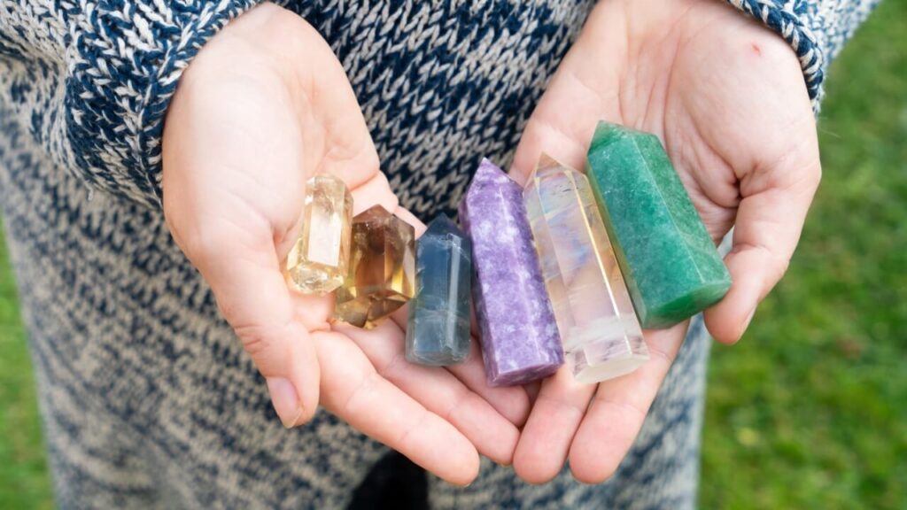 Mãos segurando um conjunto de pedras dos chakras.