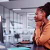 mulher negra em seu local de trabalho na frente de um computador fazendo uma oração
