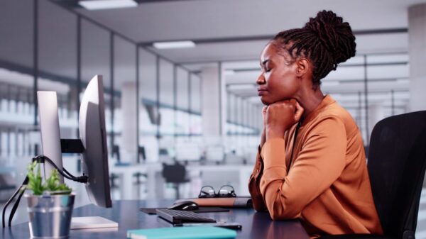 mulher negra em seu local de trabalho na frente de um computador fazendo uma oração