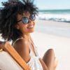 mulher negra na praia sentada em uma cadeira e sorrindo