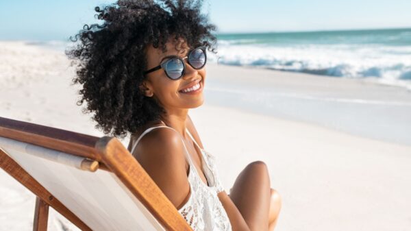 mulher negra na praia sentada em uma cadeira e sorrindo