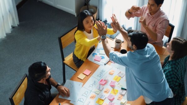 imagem de uma mesa de trabalho com uma equipe reunida ao redor