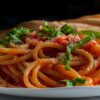 imagem de um prato branco cheio de macarrão com molho vermelho e cheiro verde