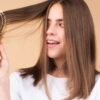 mulher passando a escova no cabelo curto em um fundo laranja claro