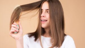 mulher passando a escova no cabelo curto em um fundo laranja claro