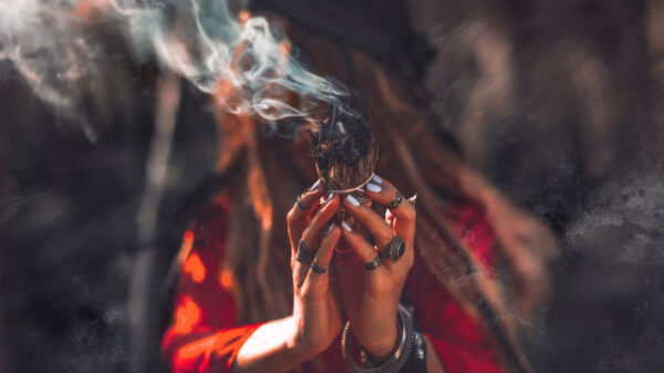 cigana com um maço de ervas defumando em suas mãos