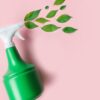 borrifador verde com folhas verdes saindo do spray em fundo rosa