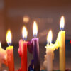 imagem de oito velas coloridas acesas uma ao lado da outra