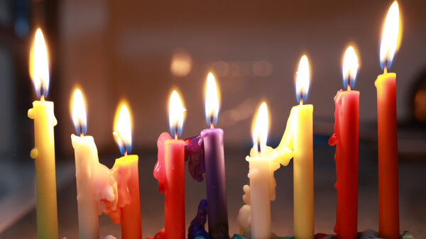 imagem de oito velas coloridas acesas uma ao lado da outra