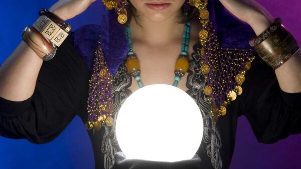 mulher com roupas ciganas olhando uma bola de cristal bastante iluminada em fundo azul e roxo