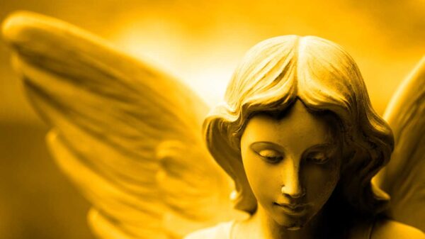 imagem da estátua de gesso em formato de anjo com uma luz amarela ao fundo