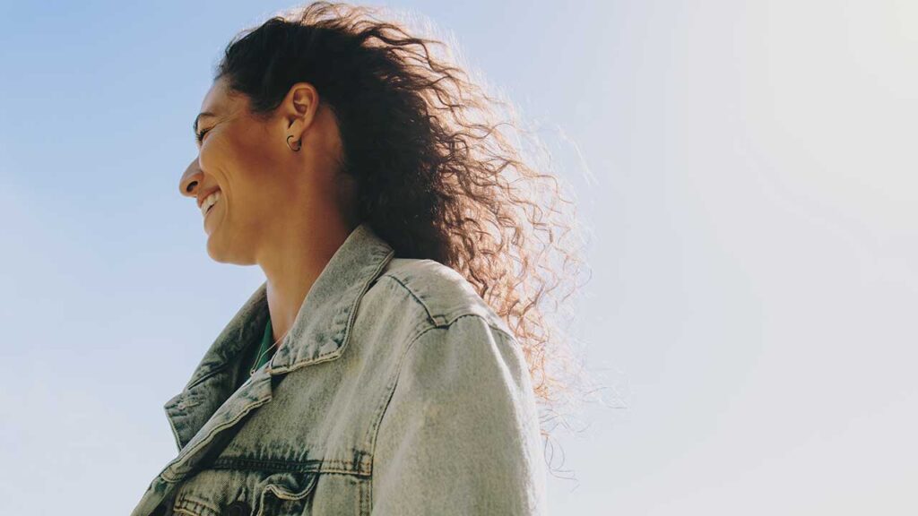 mulher sorrindo em um cenário de céu azul ao ar livre