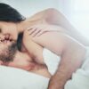 casal heterossexual abraçados deitados na cama com lençóis brancos