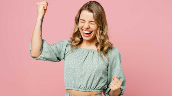 mulher em posição corporal de comemoração em fundo rosa