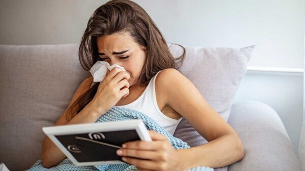 mulher deitada na cama chorando com um lenço no nariz e segurando um porta retrato