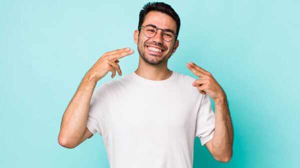 homem sorrindo e apontando o dedo para o sorriso em fundo azul
