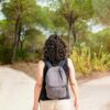 mulher de costas olhando para dois caminhos em um bosque com árvores